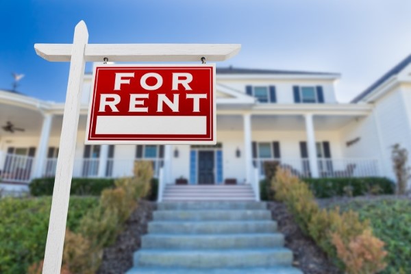 right facing for rent real estate sign in front of house.